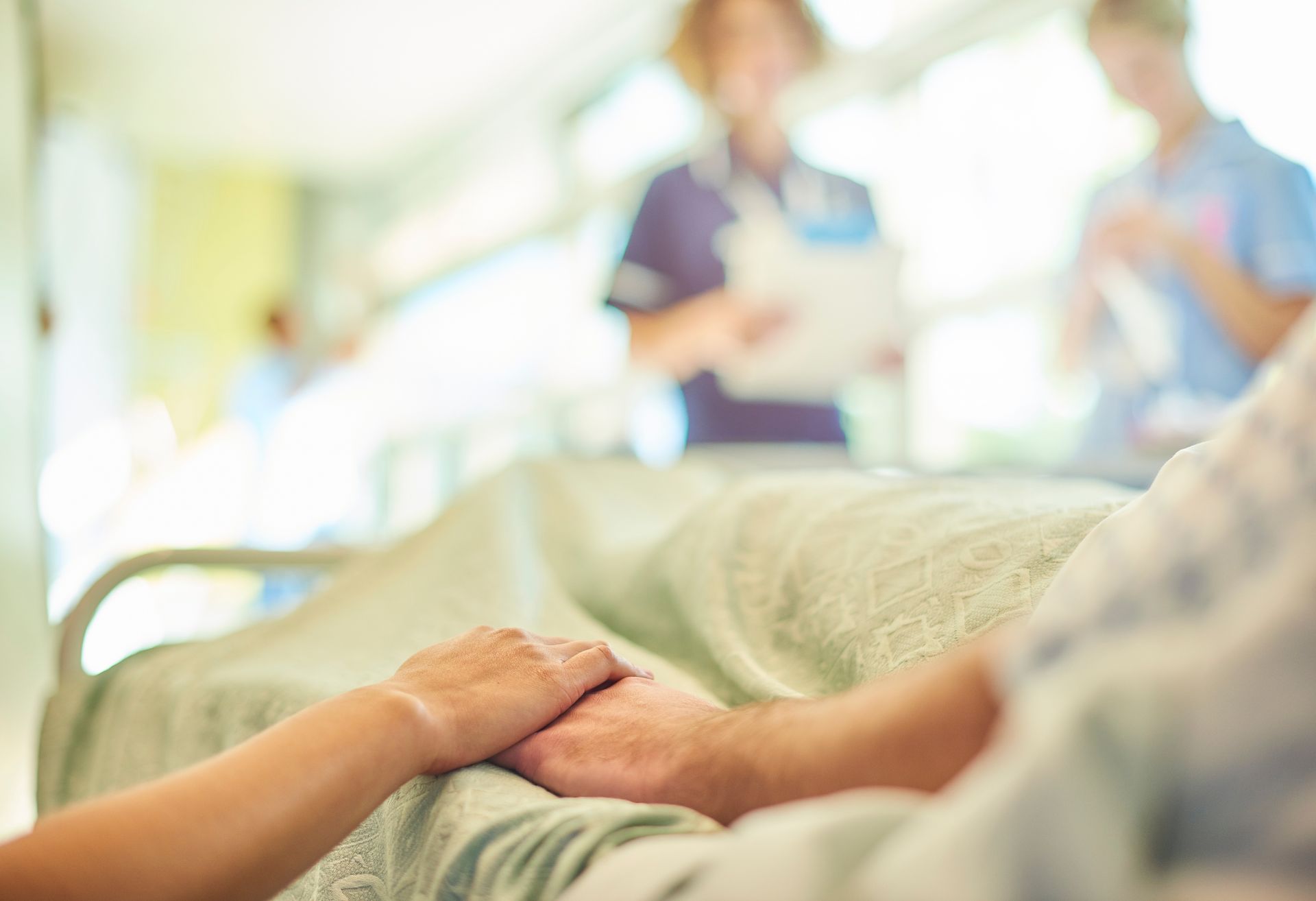 Image showing patient in a hospital bed holding a visitor's hand